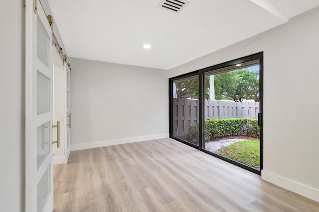 empty room with a barn door and light hardwood / wood-style floors