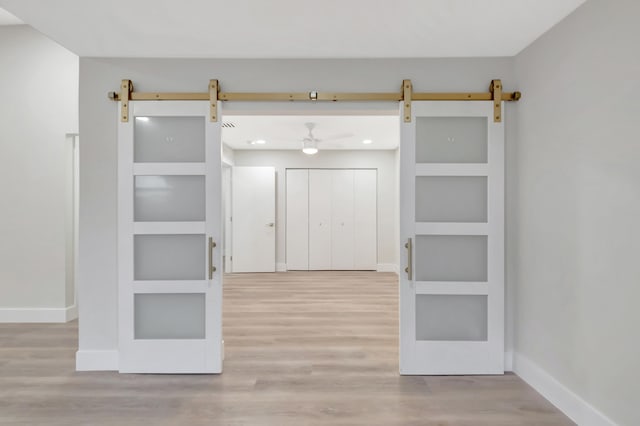 interior space with light hardwood / wood-style floors, built in features, and a barn door