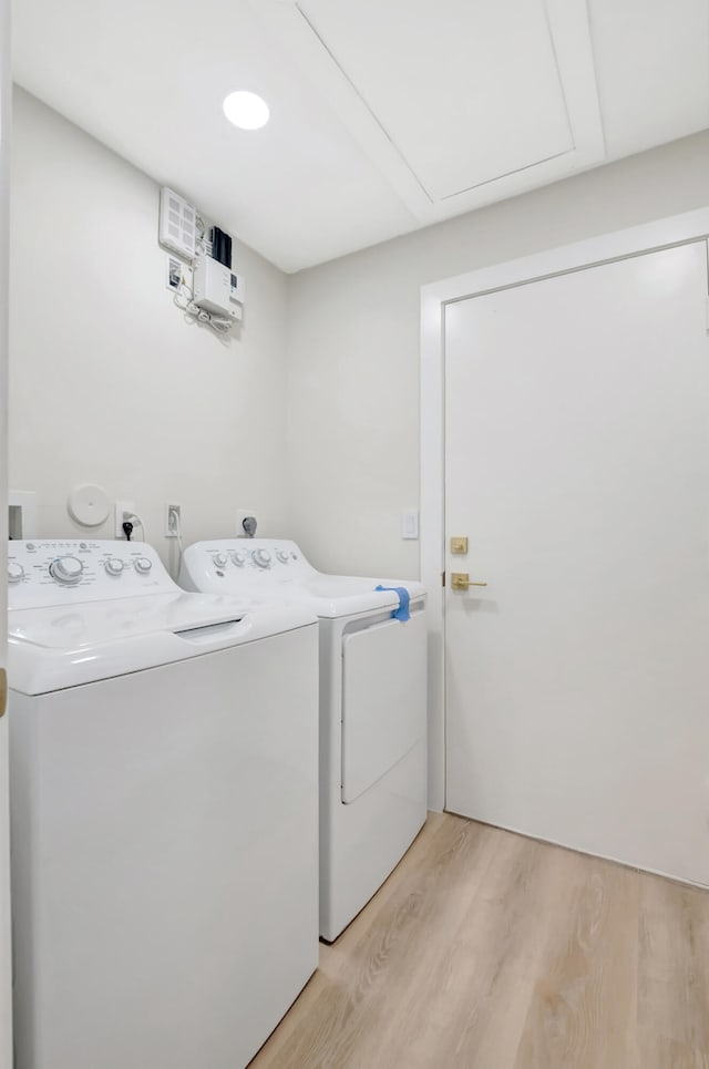 laundry room featuring washing machine and dryer and light hardwood / wood-style floors