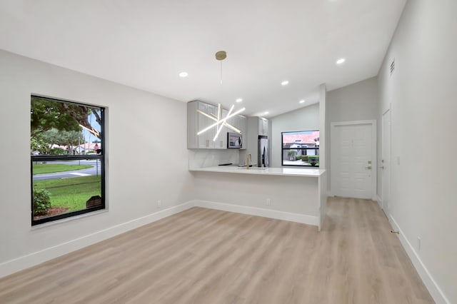 unfurnished living room with lofted ceiling, light hardwood / wood-style flooring, and sink