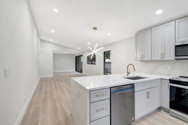 kitchen with decorative backsplash, sink, light stone counters, stainless steel appliances, and kitchen peninsula