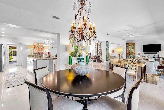 dining room featuring ceiling fan with notable chandelier and sink