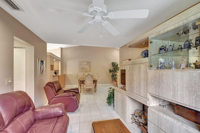 living room featuring a textured ceiling, light tile patterned floors, and ceiling fan