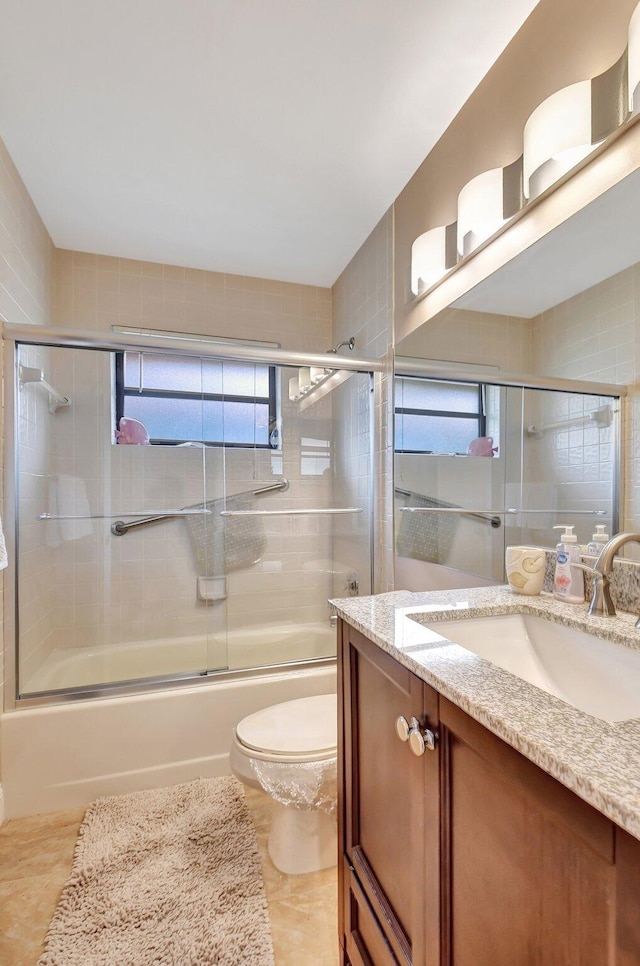 full bathroom with shower / bath combination with glass door, tile patterned flooring, toilet, and vanity