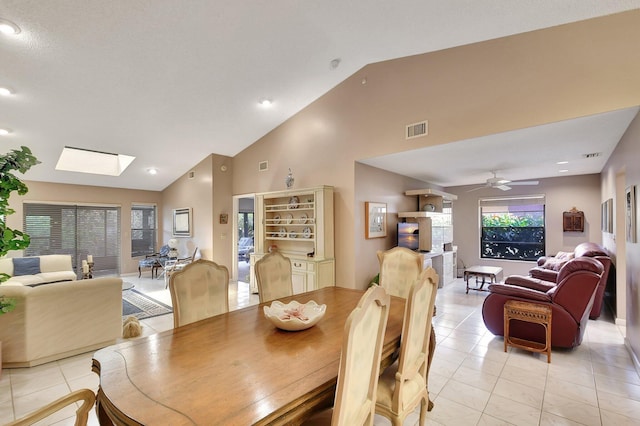 dining space featuring high vaulted ceiling, a skylight, ceiling fan, and light tile patterned flooring