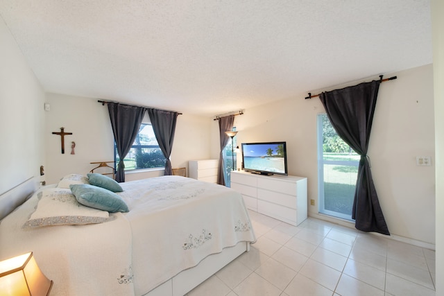 bedroom with a textured ceiling, light tile patterned flooring, and access to outside