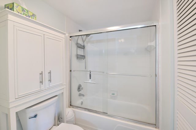 bathroom featuring toilet and bath / shower combo with glass door