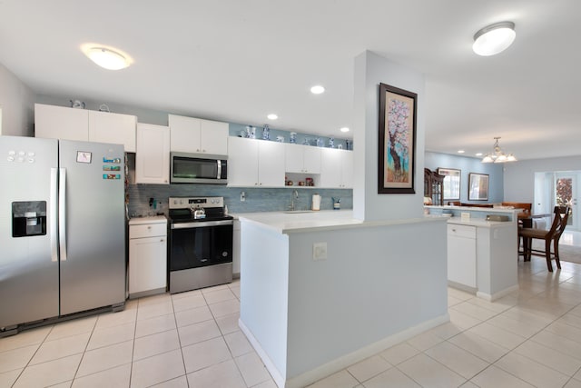 kitchen featuring a notable chandelier, kitchen peninsula, a center island, appliances with stainless steel finishes, and white cabinets