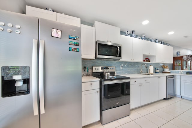 kitchen featuring white cabinetry, light tile patterned floors, stainless steel appliances, sink, and decorative backsplash