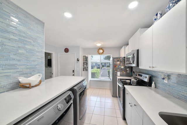 kitchen featuring light tile patterned floors, appliances with stainless steel finishes, white cabinets, and decorative backsplash