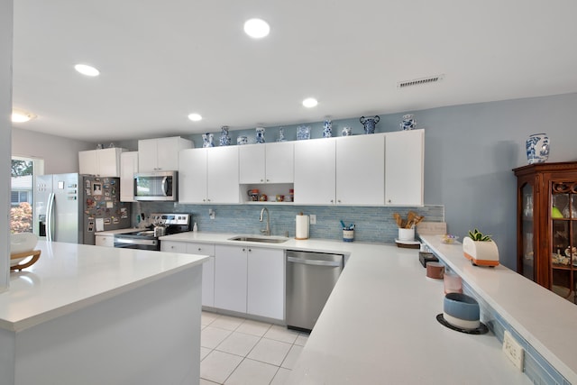 kitchen with backsplash, stainless steel appliances, white cabinetry, and sink