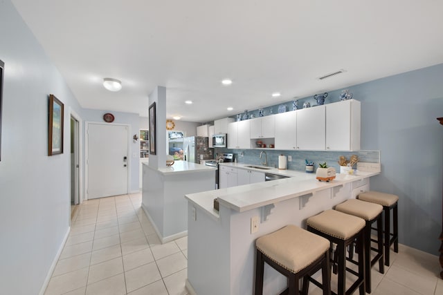 kitchen featuring white cabinets, sink, kitchen peninsula, and a breakfast bar