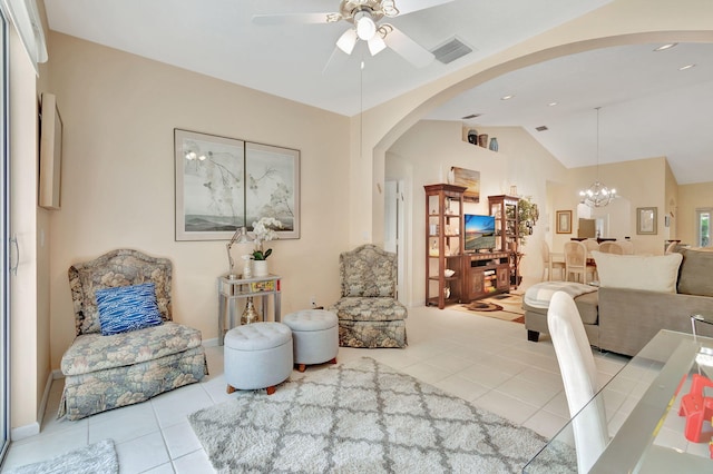 tiled living room with ceiling fan with notable chandelier and lofted ceiling