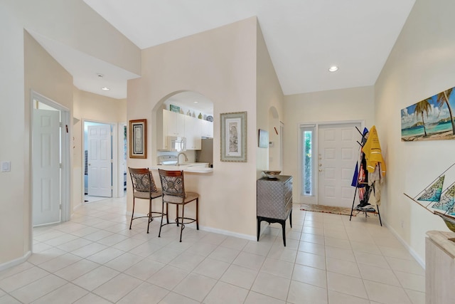 kitchen featuring kitchen peninsula, light tile patterned floors, vaulted ceiling, and white cabinets