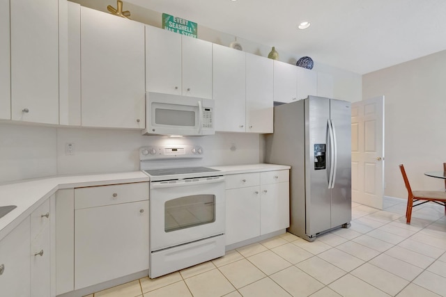 kitchen with light tile patterned floors, white appliances, and white cabinets