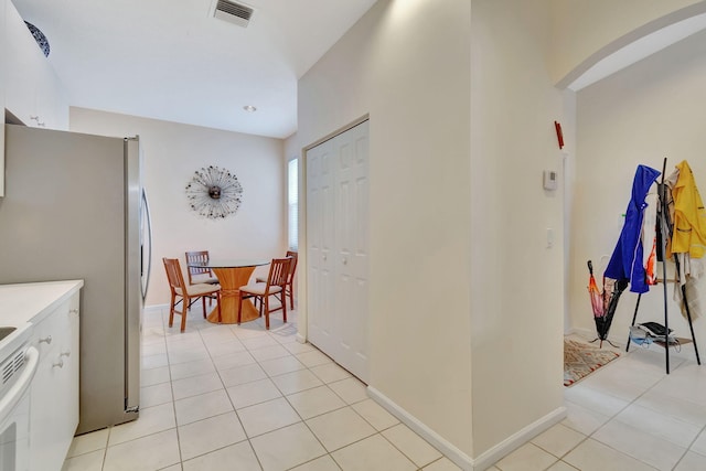 kitchen with stainless steel fridge, white cabinetry, and light tile patterned floors