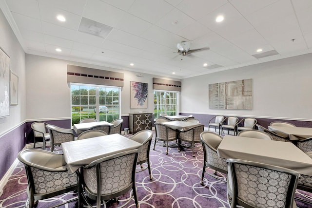 carpeted dining space featuring crown molding and ceiling fan