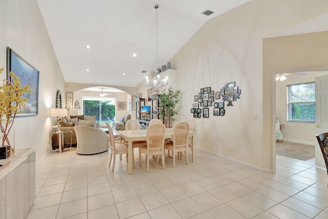 tiled dining room featuring ceiling fan with notable chandelier, high vaulted ceiling, and a wealth of natural light