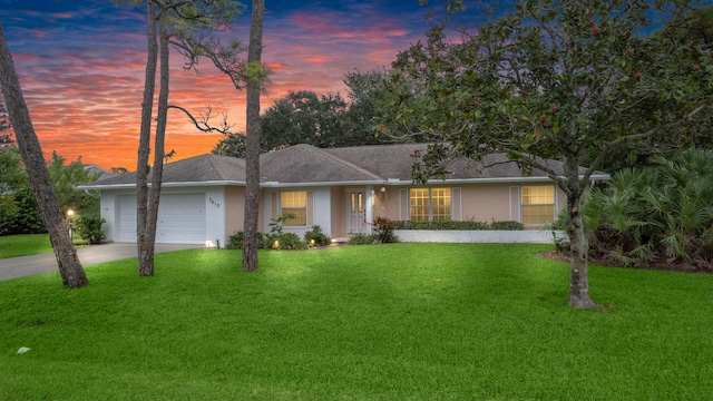 single story home with a garage and a yard