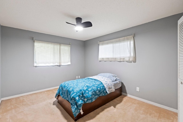 carpeted bedroom featuring multiple windows, a textured ceiling, ceiling fan, and a closet