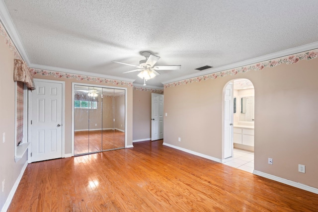 unfurnished bedroom featuring crown molding, light hardwood / wood-style flooring, ceiling fan, and a textured ceiling