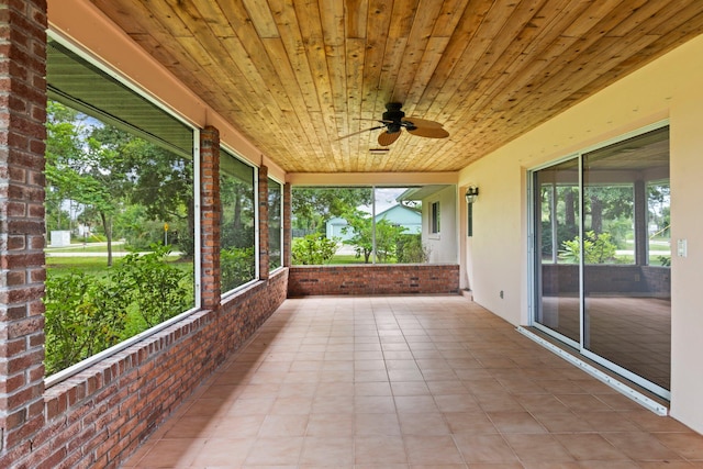 unfurnished sunroom featuring ceiling fan, wood ceiling, and plenty of natural light