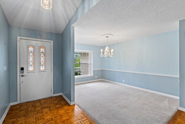 foyer entrance featuring a textured ceiling, an inviting chandelier, and carpet flooring