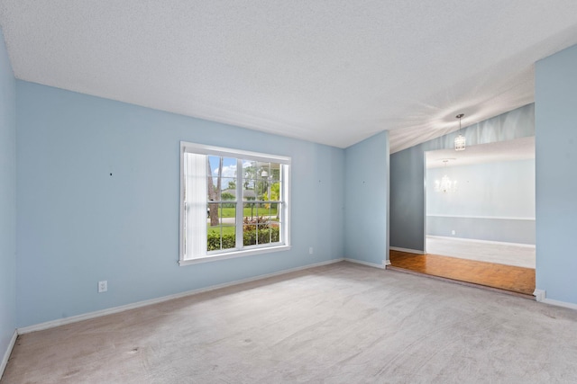 empty room featuring lofted ceiling, light colored carpet, a notable chandelier, and a textured ceiling