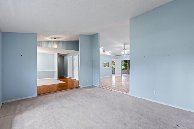 unfurnished room featuring a textured ceiling, carpet flooring, and ceiling fan