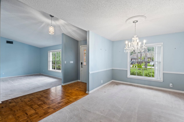 empty room featuring vaulted ceiling, a textured ceiling, an inviting chandelier, and carpet flooring