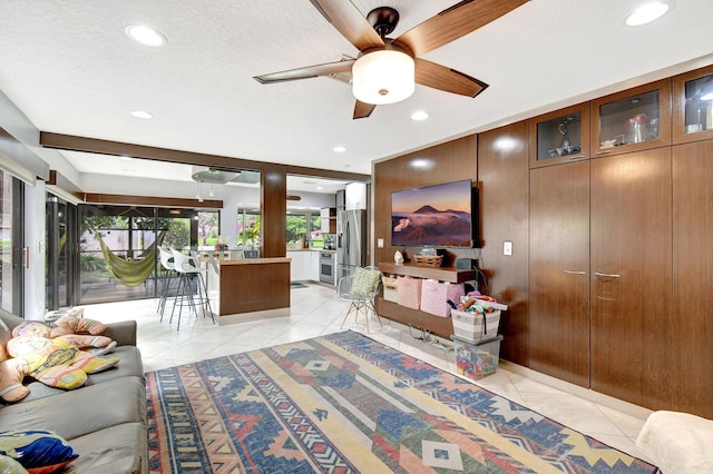 living room with light tile patterned floors, a textured ceiling, and ceiling fan