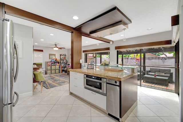 kitchen with a center island, ceiling fan, appliances with stainless steel finishes, light stone counters, and white cabinetry