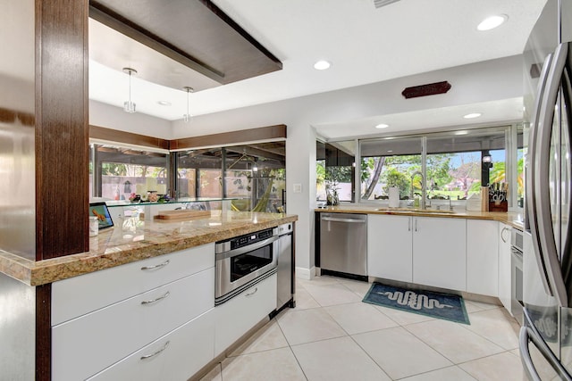 kitchen with a wealth of natural light, white cabinetry, sink, and appliances with stainless steel finishes