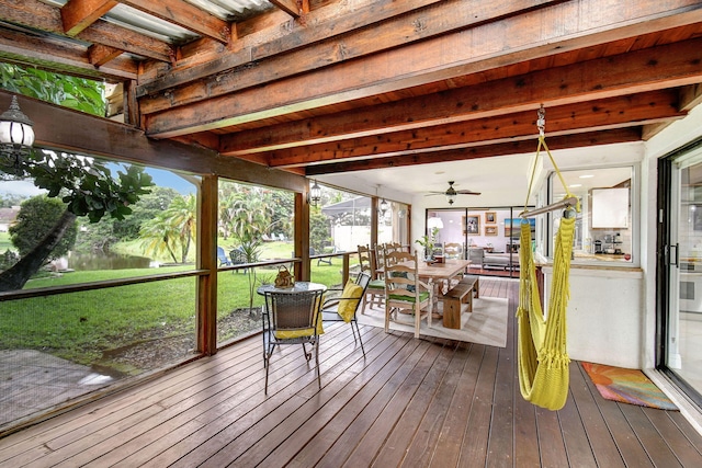 sunroom / solarium with a water view, ceiling fan, and beamed ceiling