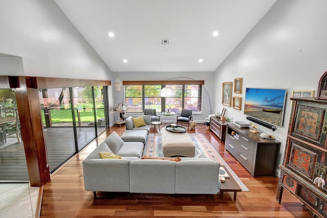 living room with light wood-type flooring and high vaulted ceiling