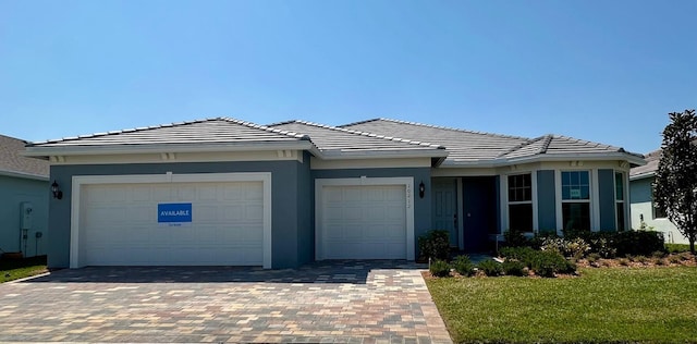 view of front of house with stucco siding, decorative driveway, and a garage