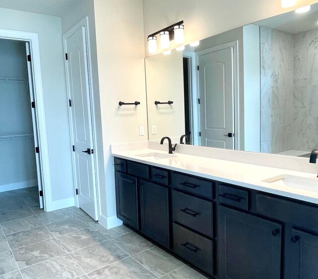 full bath with double vanity, baseboards, and a sink