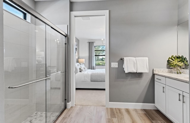 ensuite bathroom featuring vanity, wood finished floors, baseboards, a stall shower, and connected bathroom