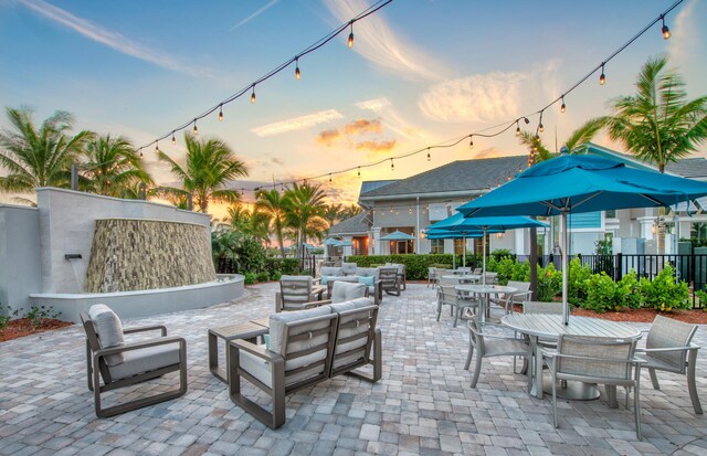 patio terrace at dusk featuring an outdoor living space, outdoor dining space, and fence