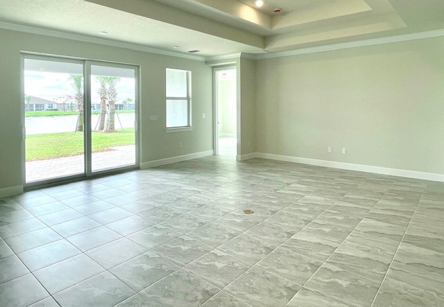 empty room with a tray ceiling, baseboards, and ornamental molding