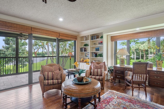 living area with a textured ceiling, dark wood-type flooring, and ornamental molding