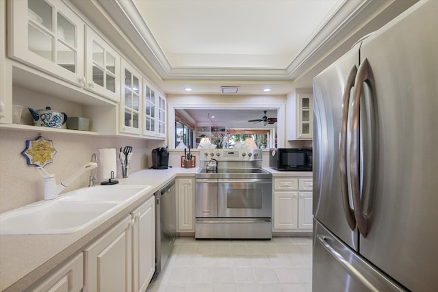 kitchen featuring white cabinets, crown molding, stainless steel appliances, a raised ceiling, and ceiling fan