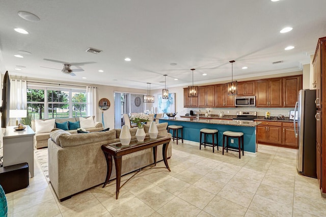 tiled living room with ceiling fan, sink, and crown molding