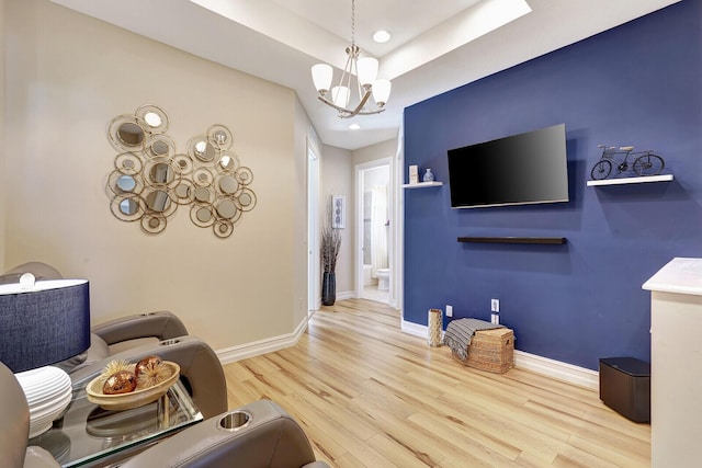 living room featuring a notable chandelier, light hardwood / wood-style floors, and a tray ceiling