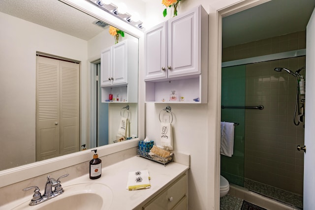 bathroom featuring a textured ceiling, an enclosed shower, vanity, and toilet