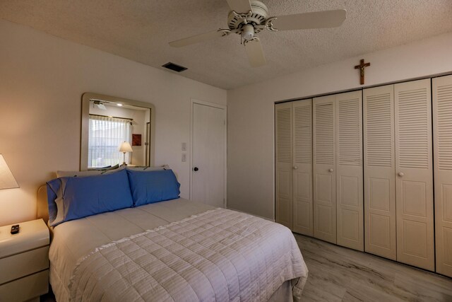 bedroom with ceiling fan, a textured ceiling, light wood-type flooring, and a closet