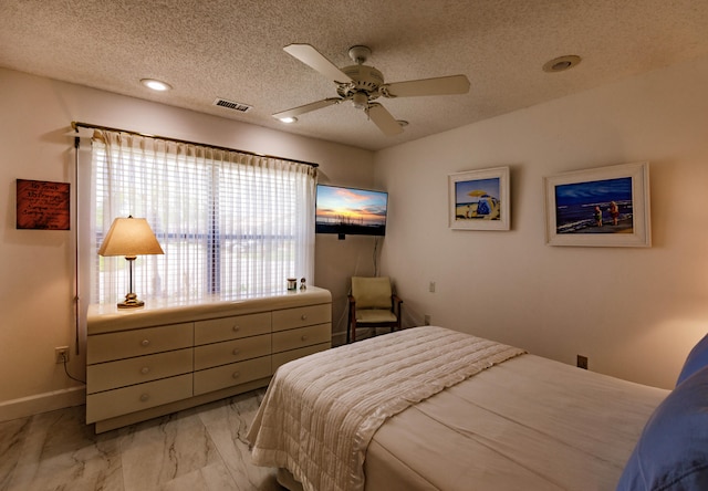 bedroom with ceiling fan and a textured ceiling