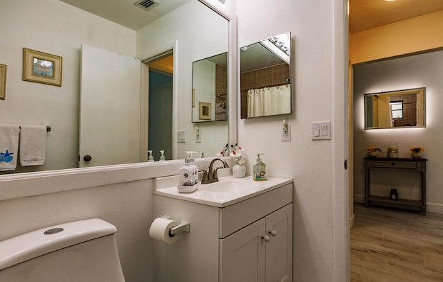 bathroom featuring wood-type flooring, vanity, and toilet