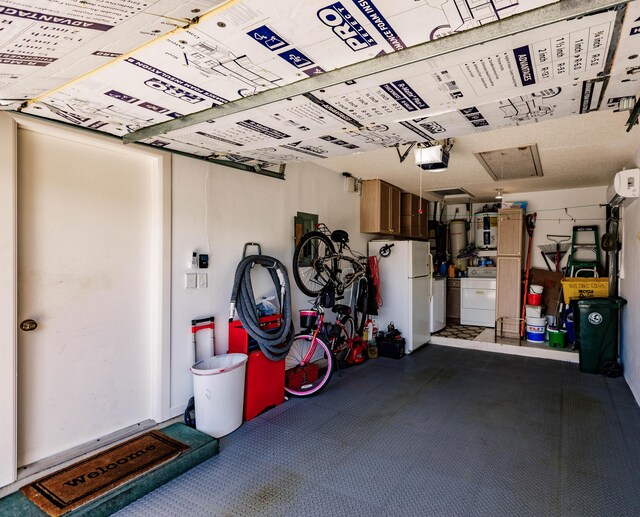 garage with a garage door opener, washer / dryer, and white fridge