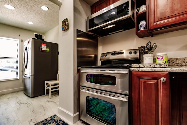 kitchen featuring light stone countertops, a textured ceiling, and appliances with stainless steel finishes